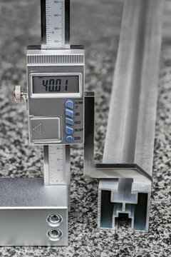 Accurate digital height gauge with metal scriber on plane granite measuring surface plate. Measurement of aluminum profile size. Marking out process to transferring dimensions by carbide drawing edge.