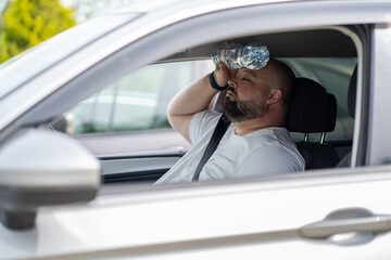 Overweight man drives car with broken air conditioner in hot summer weather. Weary male presses...