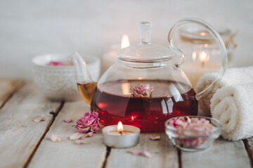 Concept of natural organic flower, herbal ingredients for spa treatment for relaxation and detox. Hot tea with rose extract, petals for beauty procedures, towel, candles for detention and meditation