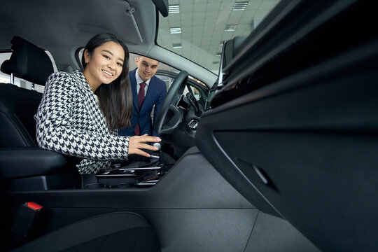 Young asian woman inspects the interior of acar before buying
