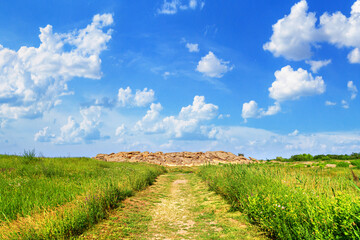 Fototapeta na wymiar Summer landscape - view of the path to the mound of sandstone boulders, a fragment of the bottom of an ancient prehistoric sea, ancient place of worship, archeological preserve Kamyana Mohyla, Ukraine