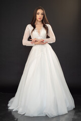 Fototapeta na wymiar Beautiful fashion bride posing in wedding dress on black background 