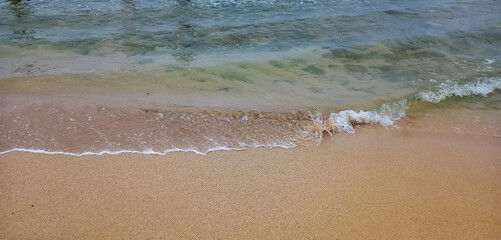 sea waves hitting white sand and coral rocks at beach with cloudy sky