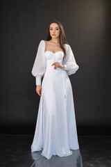Fototapeta na wymiar Beautiful fashion bride posing in wedding dress on black background 