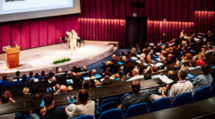 Business and entrepreneurship symposium. Female speaker giving a talk at business meeting. Audience...