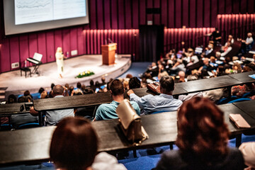 Business and entrepreneurship symposium. Female speaker giving a talk at business meeting. Audience...