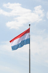 Flag of the Kingdom of Luxembourg - fluttering in the wind against a blue sky, natural photography