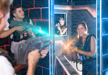 Laser tag players young mens and womens playing in teams in dark laser tag station