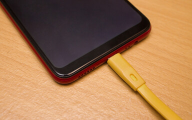 A smartphone in charge on a wooden table