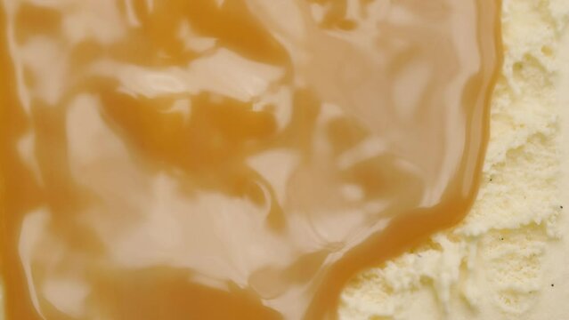 Close-up of rich, golden caramel sauce melting over creamy vanilla ice cream. The glossy texture contrasts with the smooth, frozen dessert, creating a tempting sweet treat. Marketing, adverts, promo.