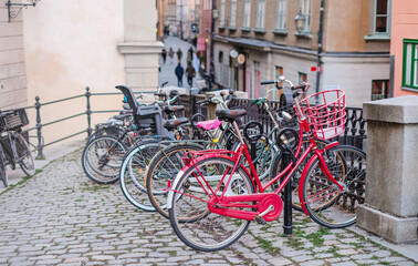 Close-up of walking bicycles with a basket parked to a pillar in the city
