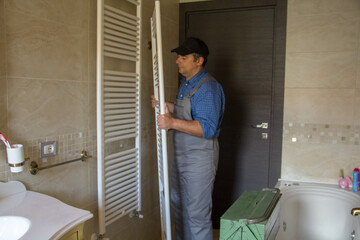 Image of a plumber while he is assembling a radiator like a towel warmer in a bathroom at home. 