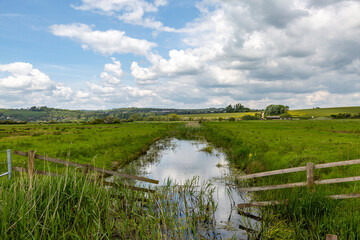 A view out over a rural Sussex landscape with a stream in springtime