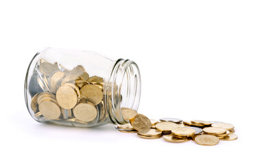 many coins spilling out of a glass jar and isolated on a white background