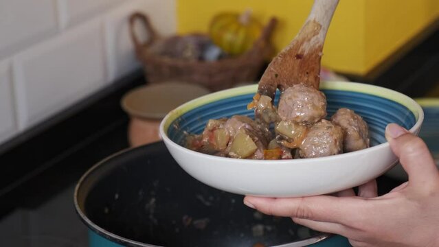 woman cooks in the kitchen of her house and prepares a traditional dish of her family food that has vegetables and meat

