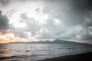 The sunsetting over an island. The photo is taken from a beach looking out into the ocean