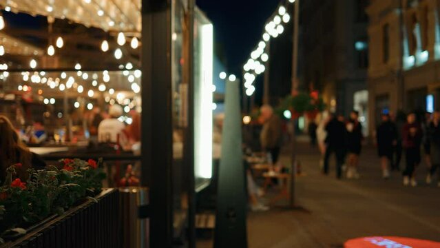 Nighttime Excitement: Blurred Establishing Shot of a City Street with Lively Restaurants and Joyful Crowds