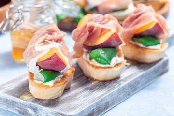 Prosciutto peach bruschetta, crostini with cream cheese, basil leaf, peach, prosciutto, horizontal