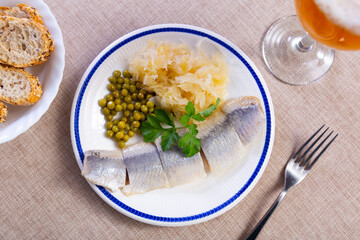 Service plate containing light salted herring with marinated cabbage and green peas