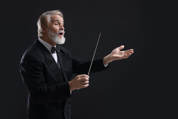 Professional conductor with baton on black background