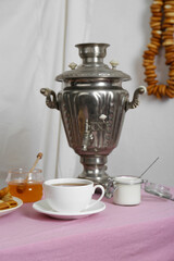 Vintage samovar, cup of hot drink and snacks served on table indoors. Traditional Russian tea...