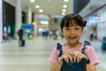 Cute happy child girl with suitcase at airport terminal. Kid and family traveling vacation for...