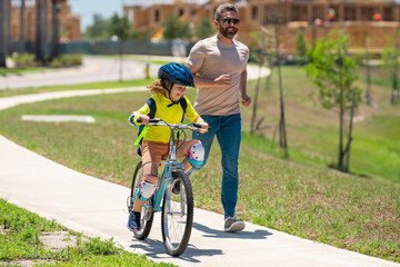 Happy fathers day. Father and son learning to ride a bicycle having fun together at Fathers day. Father teaching his son cycling on bike in american neighborhood. Father and son concept. Father