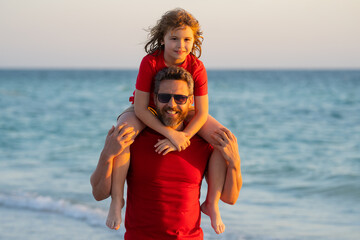 Son on fathers shoulders piggyback ride. Dad and kid son walking on the beach at the day time....