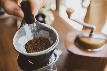 Professional hipster barista making drip brewing, filtered coffee or pour over coffee with hot water and filter paper in coffee shop cafe, black vintage tone of fresh caffeine aroma beverage