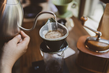 Professional hipster barista making drip brewing, filtered coffee or pour over coffee with hot...