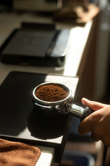 Coffee grinder with ground coffee and a cup of coffee