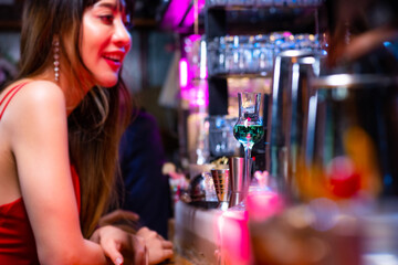 Portrait of Attractive Asian woman relax and enjoy hangout nightlife and drinking fancy cocktail at luxury restaurant bar at night. Beautiful woman celebrating holiday party at nightclub in the city.