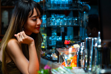 Portrait of Attractive Asian woman relax and enjoy hangout nightlife and drinking fancy cocktail at luxury restaurant bar at night. Beautiful woman celebrating holiday party at nightclub in the city.