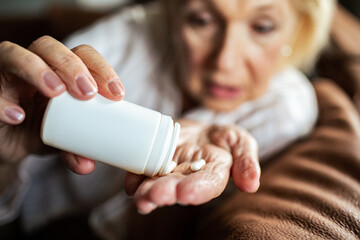 Senior woman taking a pill out of a pill bottle