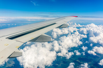 Fototapeta premium View from the airplane window at a beautiful cloudy sky and the airplane wing
