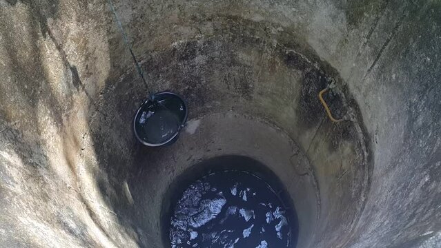 Fetching water from well with a bucket by hand, fresh pure drinking mineral water.