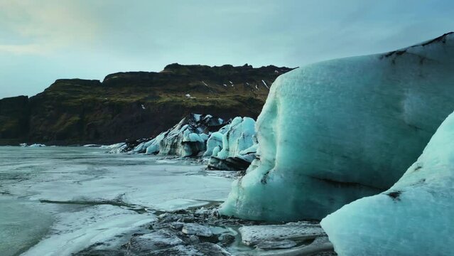 Drone shot of vatnajokull ice cap floating on nordic lake, forming beautiful arctic landscape. Icelandic scenery with huge glacier mapp and lagoon with frosty icebergs. Slow motion.