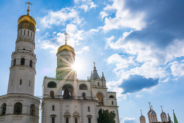 Ivan the Great Bell Tower, with Assumption Belfry on the right in Moscow Kremlin. Blue sky background with sunbeams