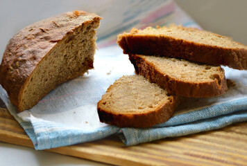 Slices of brown bread on a wooden cutting board. Selective focus.