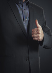 Businessman with thumb up gesture. Unrecognizable man showing thumb up gesture on dark blue...