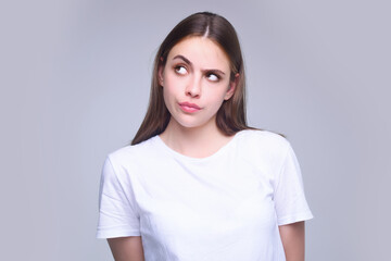 Fototapeta premium Thougthful thinking woman looks pensively aside makes plannings isolated on gray background. Beauty woman considers. Portrait of pensive thinking woman. Thoughtful girl thinking decision.