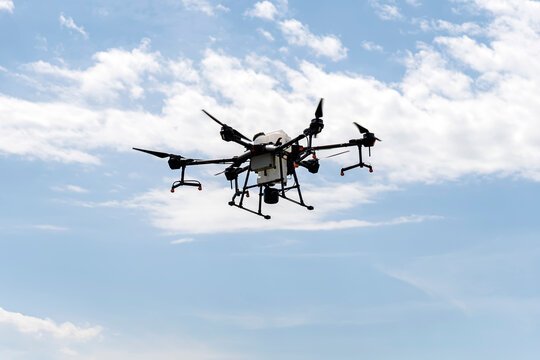 Agriculture drone flying in blue sky. Quadrocopter for pollination of plants. Modern technologies in agriculture.