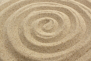 Fototapeta na wymiar A spiral is drawn on the sand.