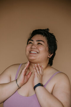 portrait of a plus size filipino woman with hands on neck smiling