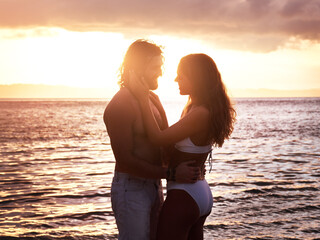 Happy couple, hug and sunset at the beach for love, quality time or bonding together in the water. Man and woman hugging in loving romance, sunrise or sunshine in the ocean for romantic holiday