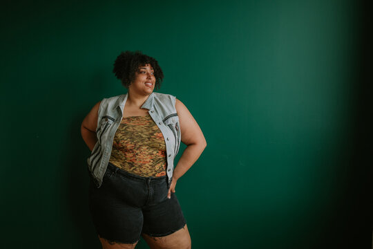portrait of a plus size afro indigenous person standing in front of green background