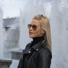 Beautiful girl of European appearance in sunglasses near the fountain.