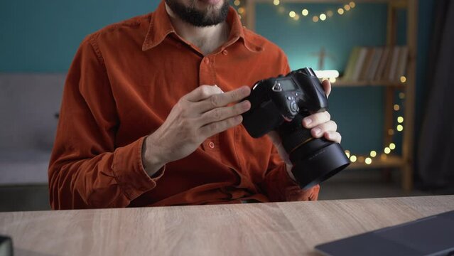 Professional photographer man remove memory card from camera, using laptop sitting at workplace indoors. Professional photography and creative career