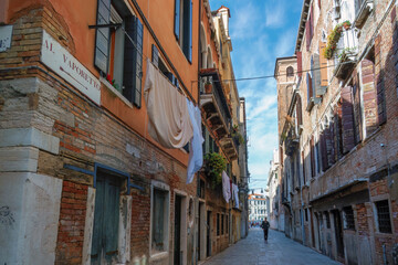 A narrow street of Venice with a male silhouette in the distance. The Center of Tourism and Travel in Europe.