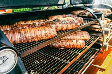 Large barbecue smoker grill at the park. Meat and bacon prepared in barbecue smoker.